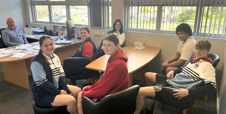 Principal sits in office with six Year 12 students from the Leadership Team