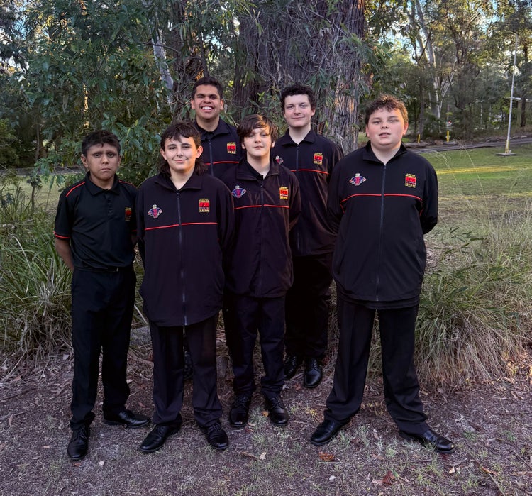 Six boys outside wearing black Clontarf jackets in front of big tree