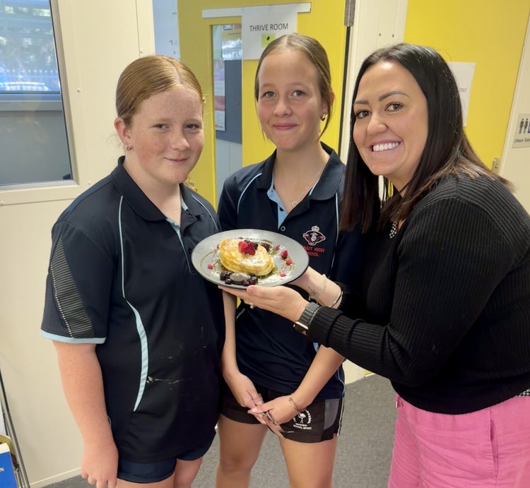Student Support Officer with 2 students with pancakes standing in the Wellbeing Hub