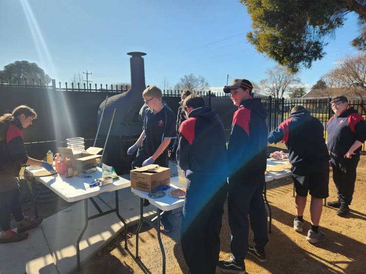 Students preparing pizzas at the school Pizza Oven outside at Wellbeing Hub